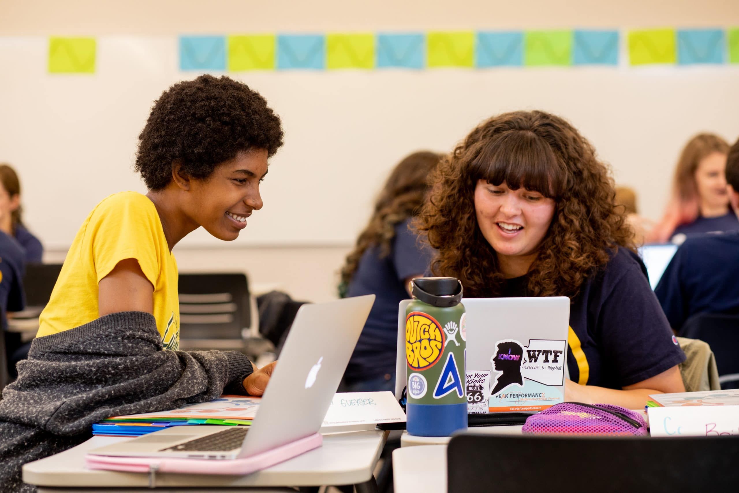 Students talking and looking at laptops.