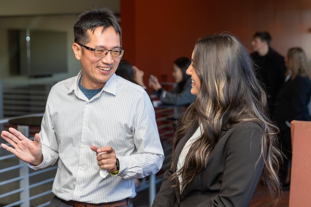 A professor and student talk in the W. A. Franke College of Business.
