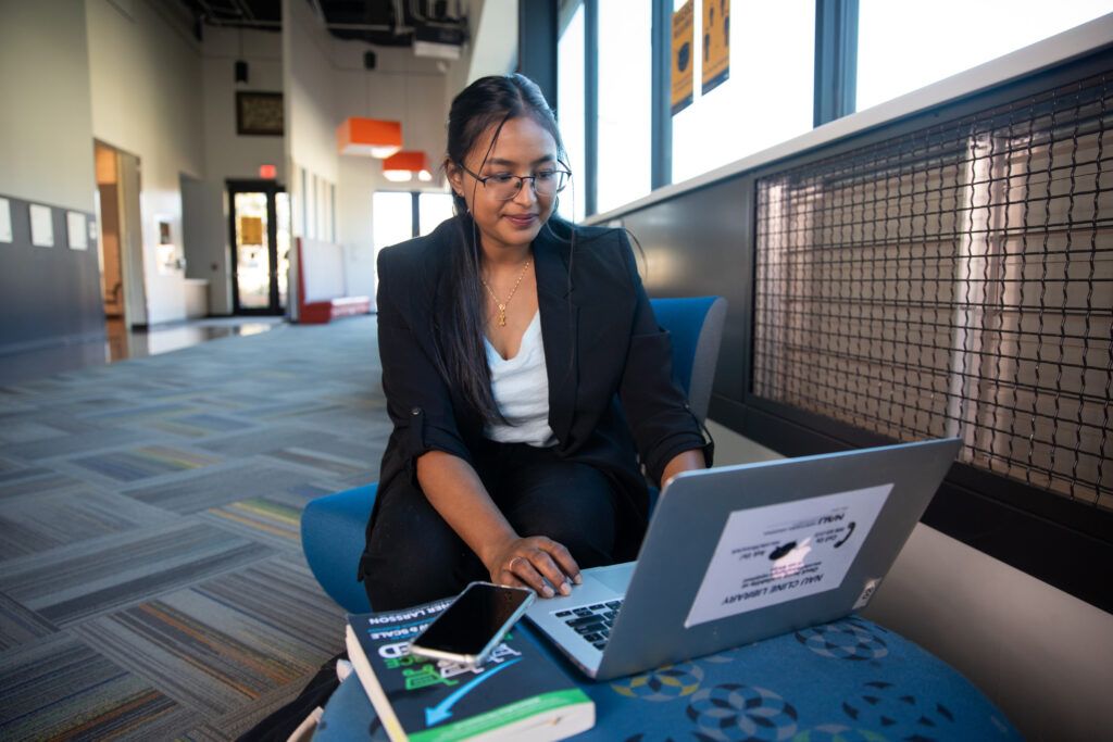 N A U student typing on a laptop in the lobby of the International Pavilion.