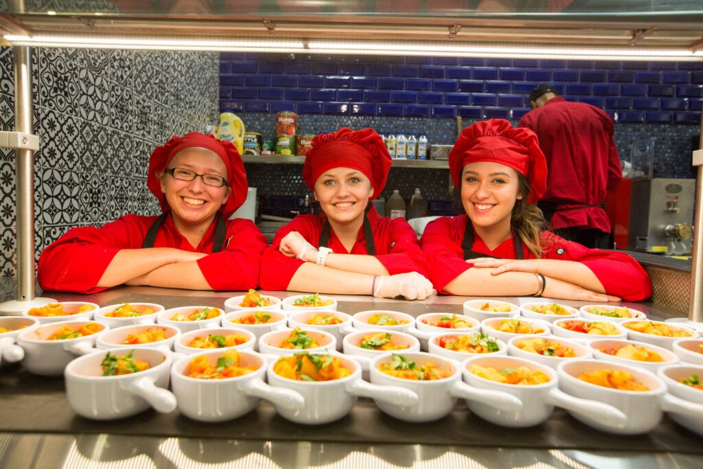 Chef's at one of N A U's Italian eateries pose with bowls of pasta.