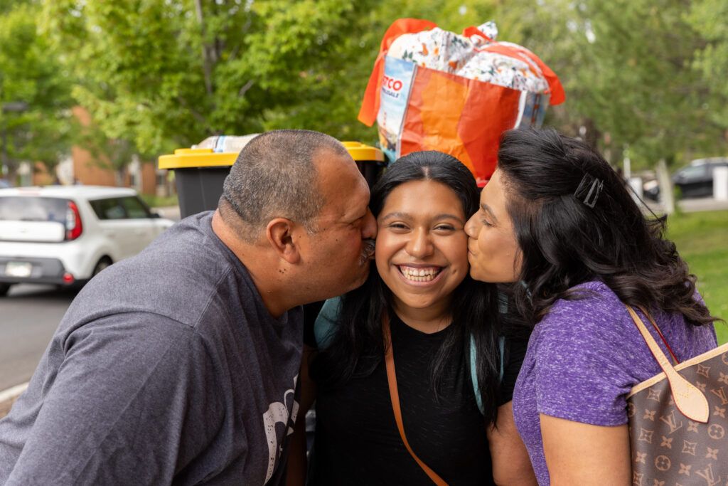 Mom and Dad kiss their N A U student on the cheeks.