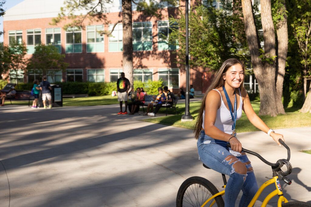 N A U student riding a Yellow Bike on campus.