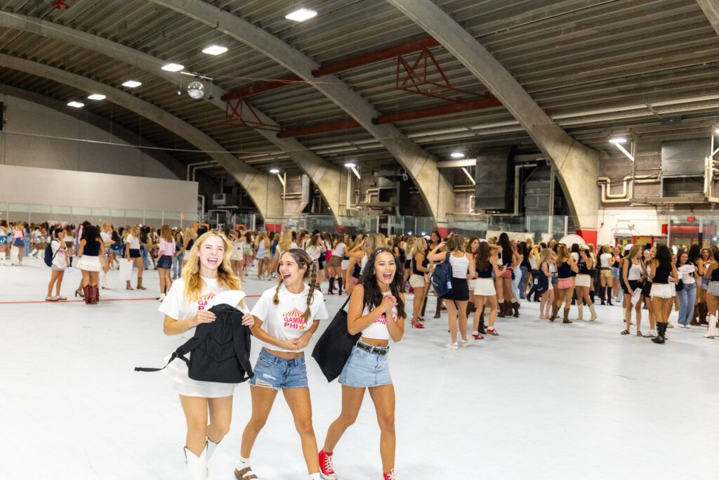 Three students candidly smiling at sorority Bid day in the Fieldhouse at Northern Arizona University.