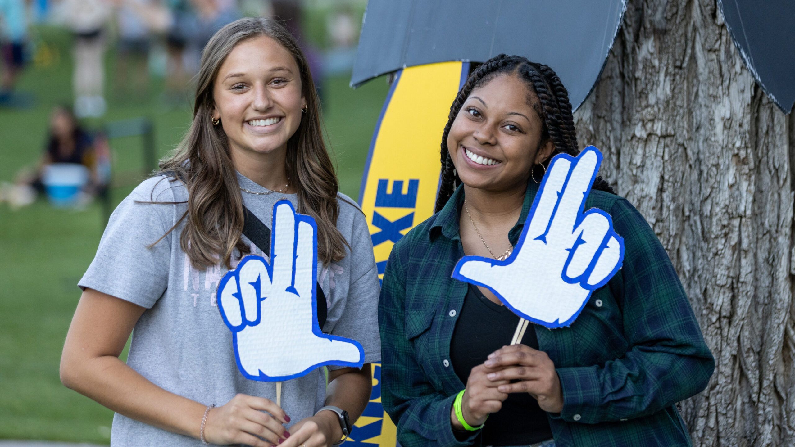 Two N A U student smiling and posing with Jacks hand signs.