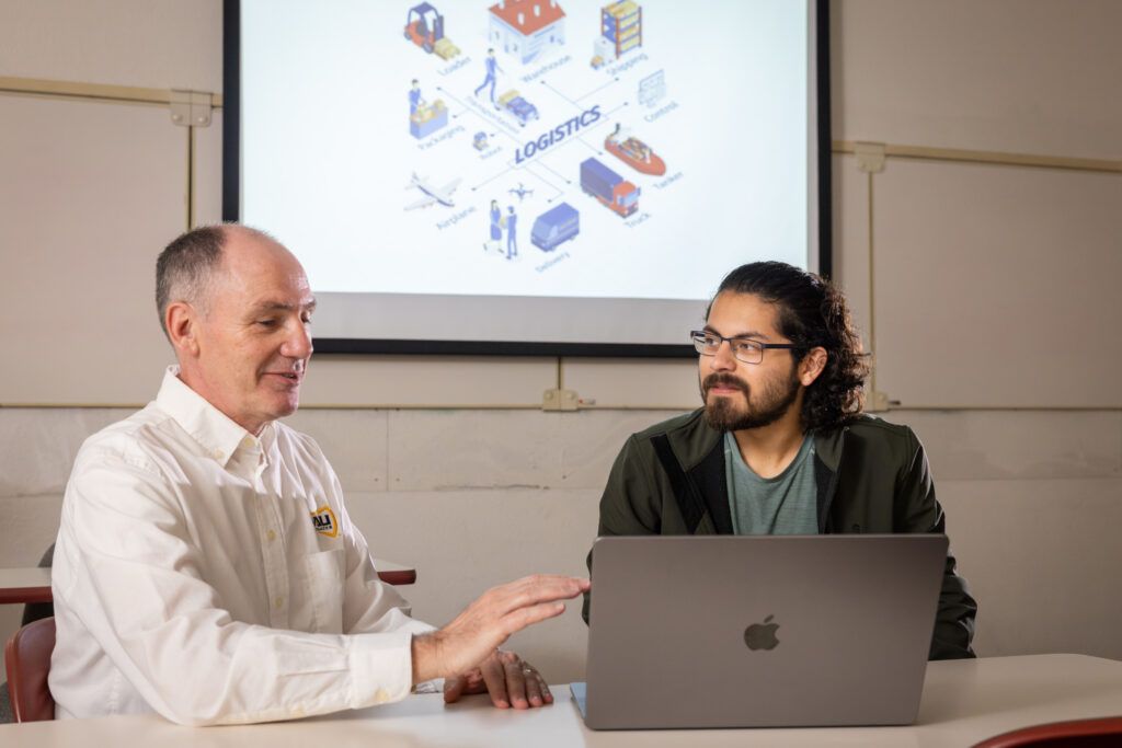 A NAU professor and a business student evaluate logistic plans on the computer.